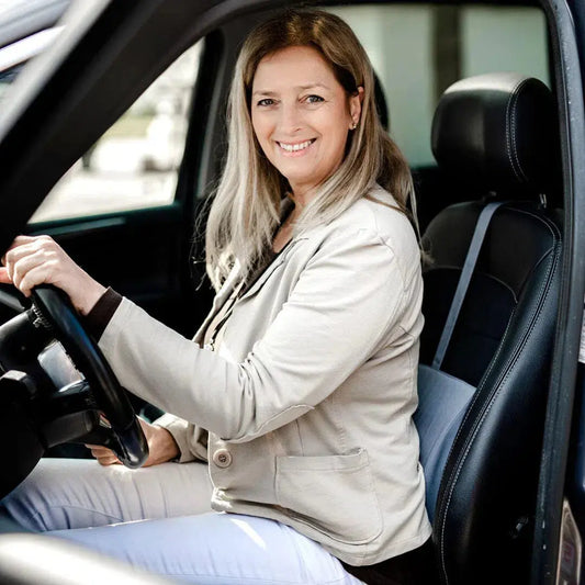 Nő vezet egy autót, a háta mögött az autós ülésben-Benergo ergonomikus tartásjavító deréktámasz védi a gerincét