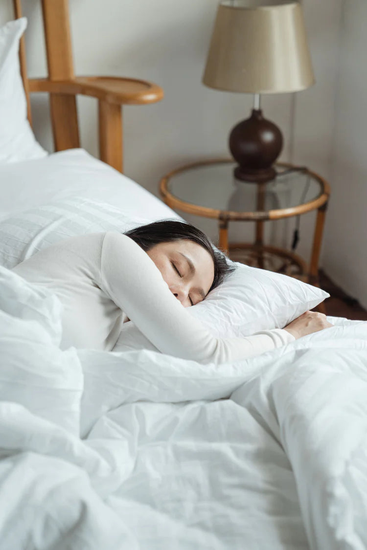 Nő alszik békésen az ágyban a fehér ágyneműben. Téma: gerincbarát alvás