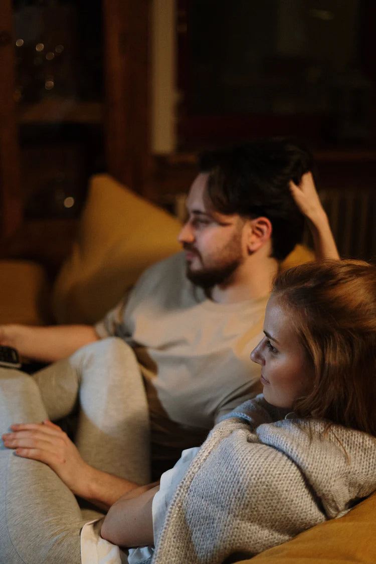Junges Paar schaut auf dem Sofa fern. Auch dabei kann die Benergo Lendenrolle die Haltung unterstützen.